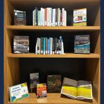 Photo of bookshelf with earth month related titles sitting on the shelf.